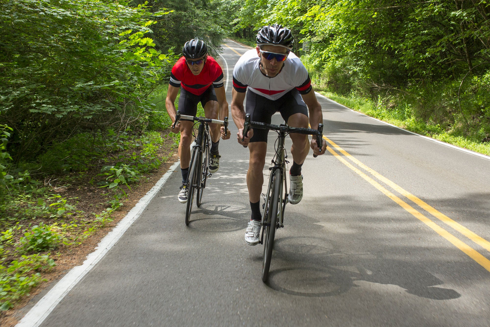 Two Men Cycling Down Road